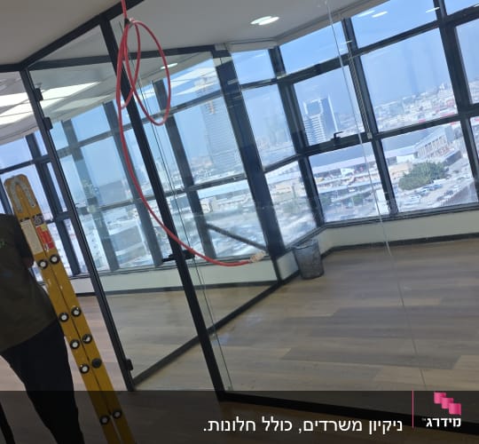 ניקוי חלונות במשרד עם דלי וסולם